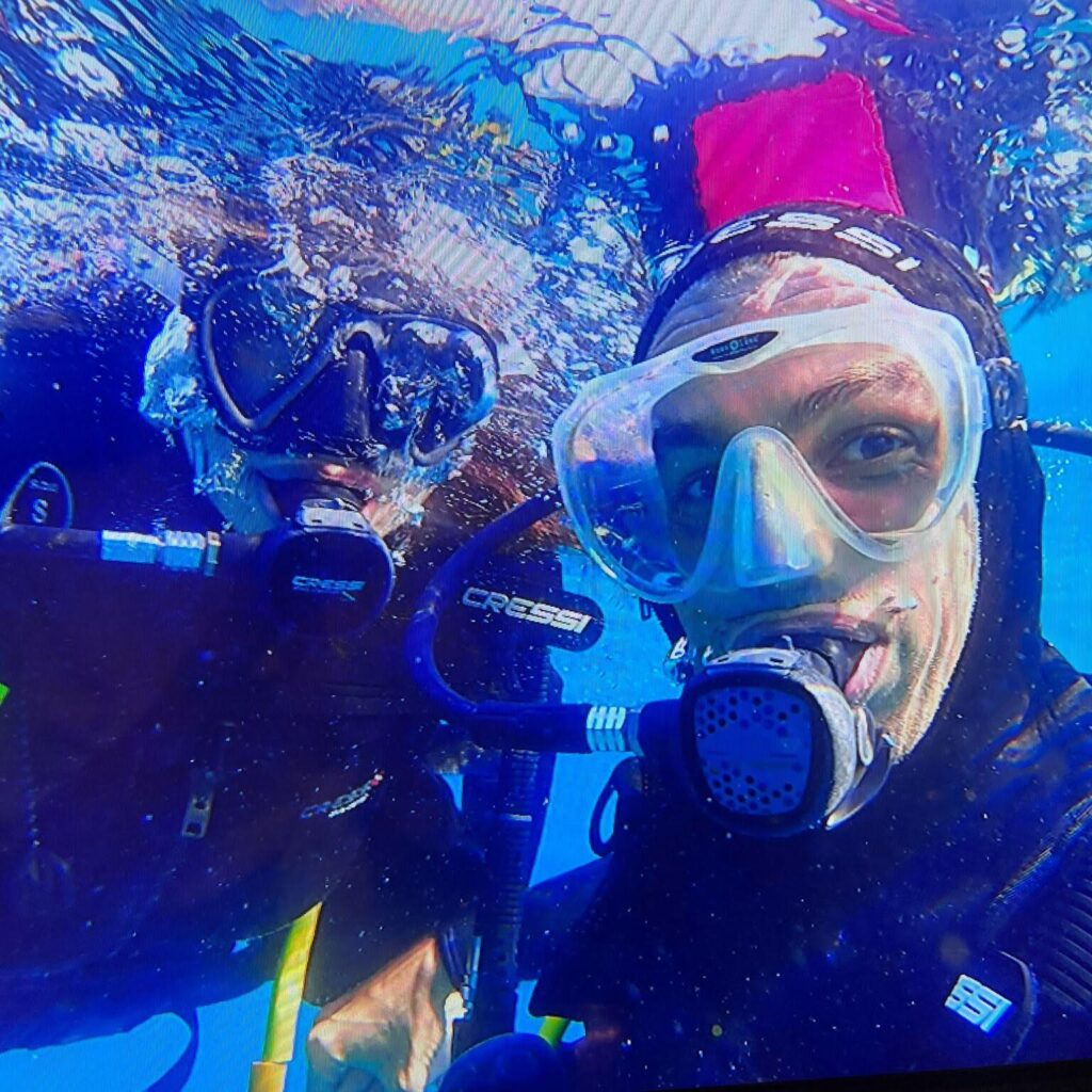 Instructor de buceo y su alumno en un bautizo de buceo en el mar.